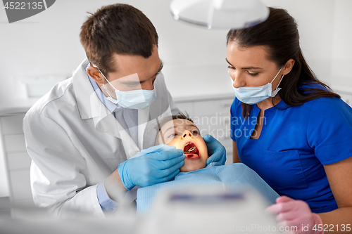 Image of dentist checking for kid teeth at dental clinic