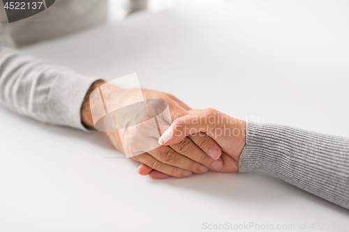 Image of close up of young woman holding senior man hands