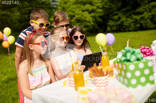 Image of happy kids with tablet pc on birthday party