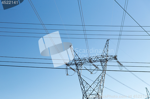 Image of transmission tower and power line over blue sky