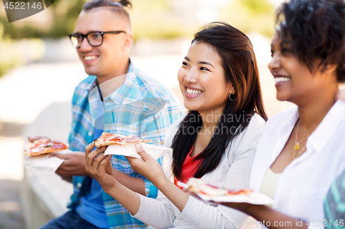 Image of happy friends eating sandwiches and pizza outdoors