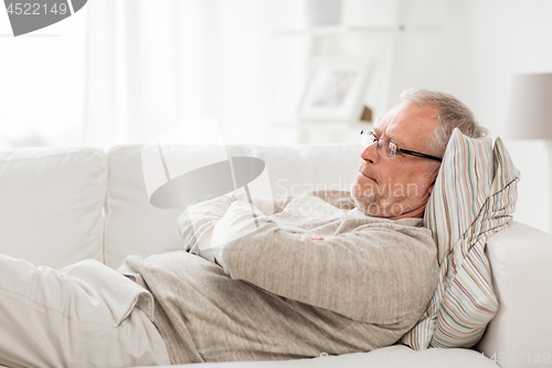 Image of thoughtful senior man lying on sofa at home