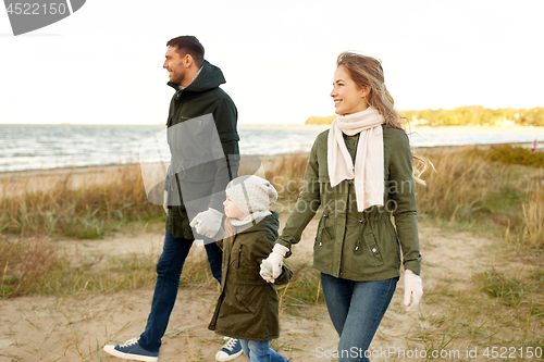 Image of happy family walking along autumn beach