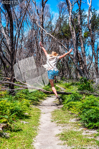 Image of Girl outdoors jumping over tree fallen across track