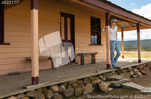 Image of Happy relaxed female on verandah of old timber home in the rural countryside