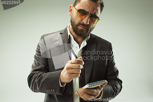 Image of Male beauty concept. Portrait of a fashionable young man with stylish haircut wearing trendy suit posing over gray background.