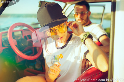 Image of Laughing romantic couple sitting in car while out on a road trip