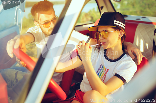 Image of Laughing romantic couple sitting in car while out on a road trip