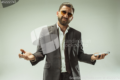 Image of Male beauty concept. Portrait of a fashionable young man with stylish haircut wearing trendy suit posing over gray background.