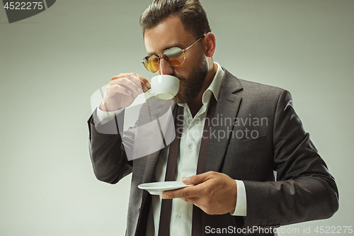 Image of Male beauty concept. Portrait of a fashionable young man with stylish haircut wearing trendy suit posing over gray background.