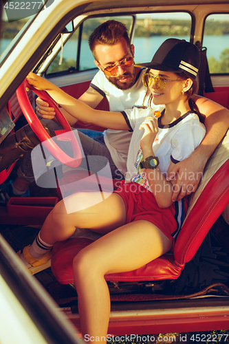 Image of Laughing romantic couple sitting in car while out on a road trip