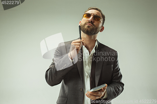 Image of Male beauty concept. Portrait of a fashionable young man with stylish haircut wearing trendy suit posing over gray background.