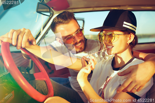 Image of Laughing romantic couple sitting in car while out on a road trip