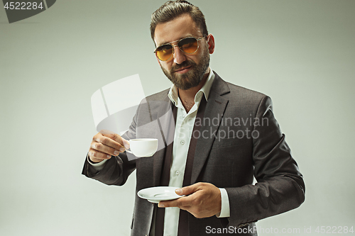 Image of Male beauty concept. Portrait of a fashionable young man with stylish haircut wearing trendy suit posing over gray background.