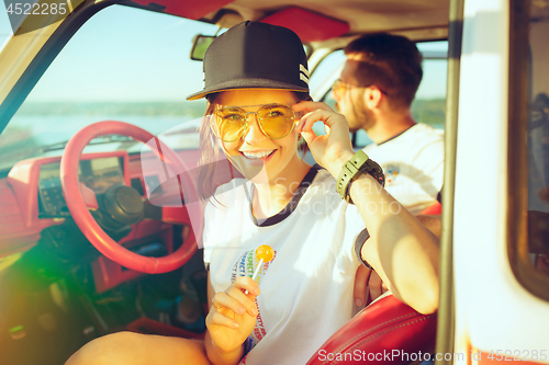 Image of Laughing romantic couple sitting in car while out on a road trip