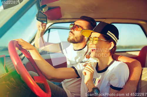 Image of Laughing romantic couple sitting in car while out on a road trip