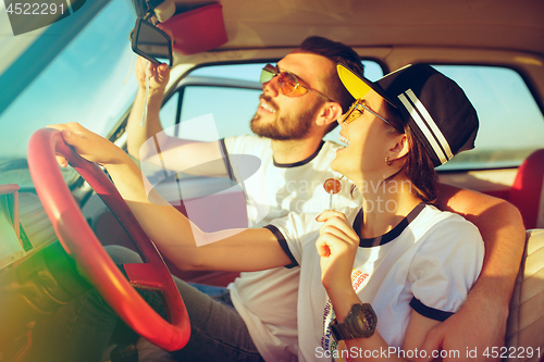 Image of Laughing romantic couple sitting in car while out on a road trip