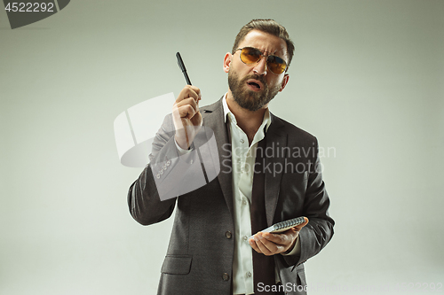 Image of Male beauty concept. Portrait of a fashionable young man with stylish haircut wearing trendy suit posing over gray background.