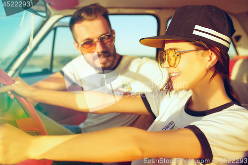 Image of Laughing romantic couple sitting in car while out on a road trip