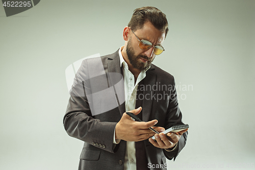 Image of Male beauty concept. Portrait of a fashionable young man with stylish haircut wearing trendy suit posing over gray background.