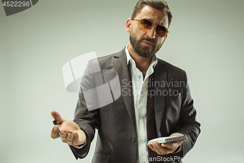 Image of Male beauty concept. Portrait of a fashionable young man with stylish haircut wearing trendy suit posing over gray background.