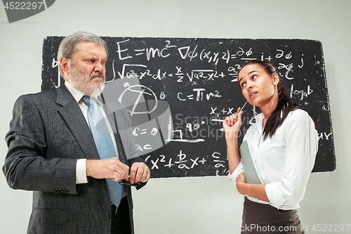Image of Male professor and young woman against chalkboard in classroom