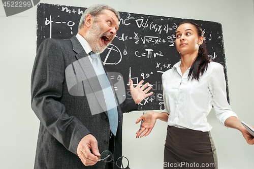 Image of Male professor and young woman against chalkboard in classroom