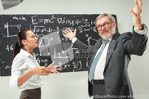 Image of Male professor and young woman against chalkboard in classroom