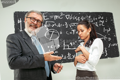 Image of Male professor and young woman against chalkboard in classroom