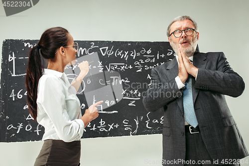 Image of Male professor and young woman against chalkboard in classroom