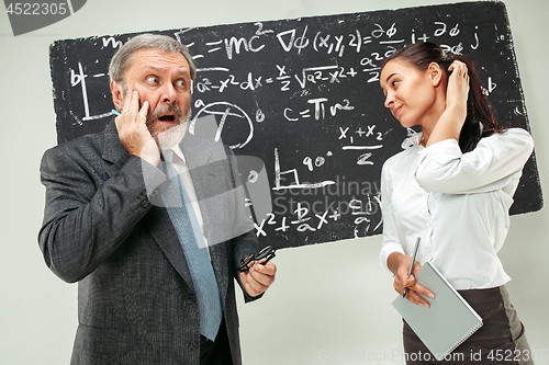 Image of Male professor and young woman against chalkboard in classroom