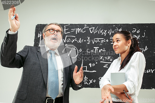 Image of Male professor and young woman against chalkboard in classroom