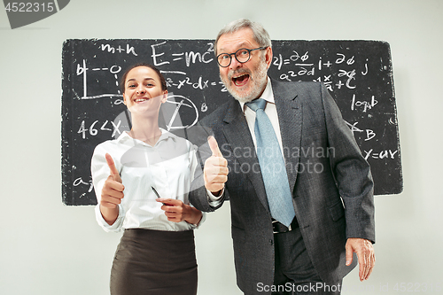 Image of Male professor and young woman against chalkboard in classroom