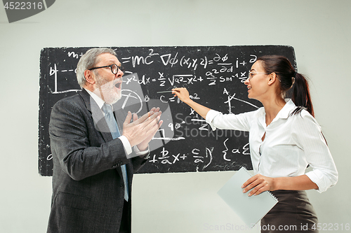 Image of Male professor and young woman against chalkboard in classroom