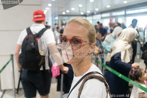 Image of Young female traveler waiting in long line at security check at the departure airport terminal. Lady standing in long queue at airport before boarding a plane.