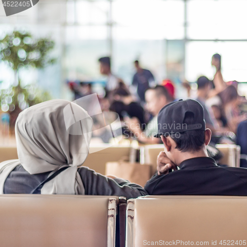 Image of Modern muslim islamic asian couple sitting and waiting for flight departure at international airport terminal