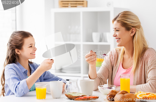 Image of happy mother and daughter having breakfast at home