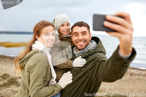 Image of family taking selfie by smartphone on autumn beach