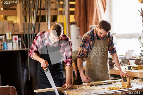 Image of carpenters working with saw and wood at workshop