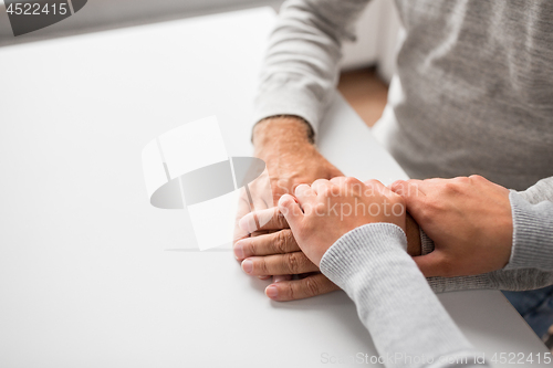 Image of close up of young woman holding senior man hands