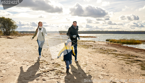 Image of happy family running along autumn beach
