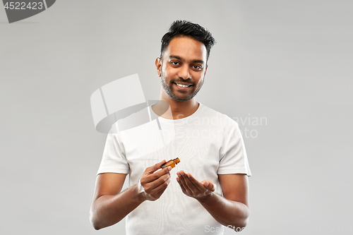 Image of indian man applying grooming oil to his hand