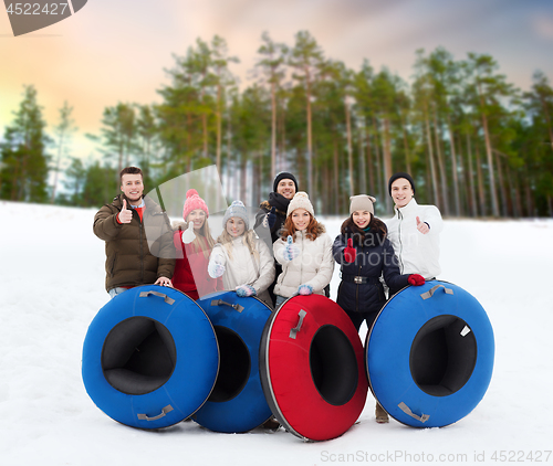 Image of happy friends with snow tubes outdoors in winter