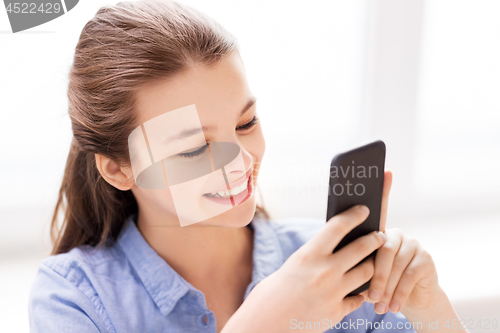 Image of smiling girl messaging on smartphone at home