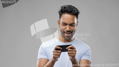 Image of happy indian man playing game on smartphone