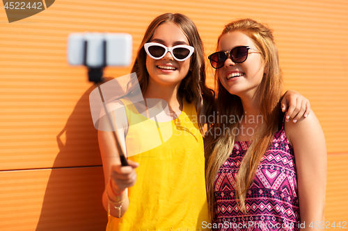 Image of teenage girls taking picture by selfie stick