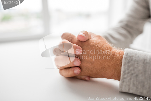 Image of senior man hands on table
