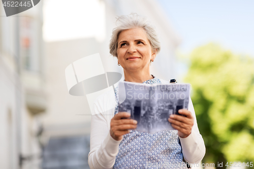 Image of senior woman or tourist with city guide outdoors