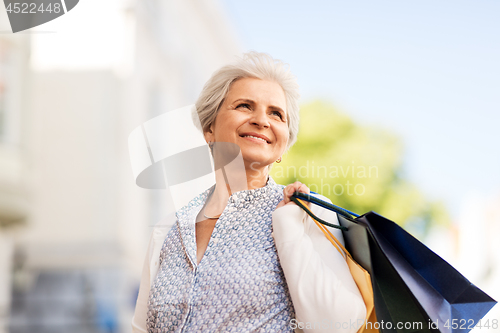 Image of senior woman with shopping bags in city