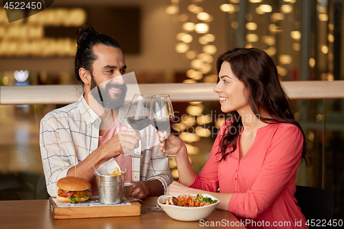 Image of couple eating and drinking red wine at restaurant